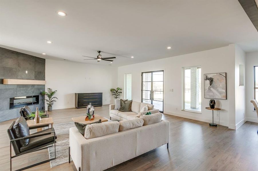 Living area featuring recessed lighting, a ceiling fan, light wood-style floors, and a fireplace Living area featuring recessed lighting, a ceiling fan, light wood-style floors, and a fireplace