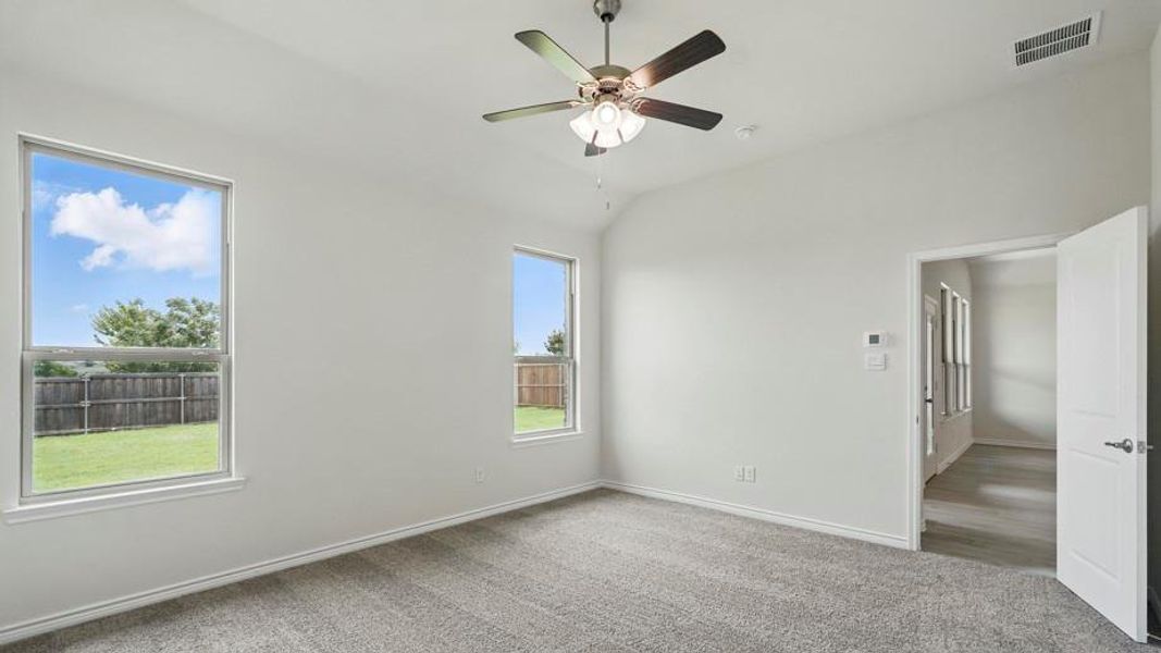 Unfurnished bedroom featuring light carpet, lofted ceiling, and ceiling fan