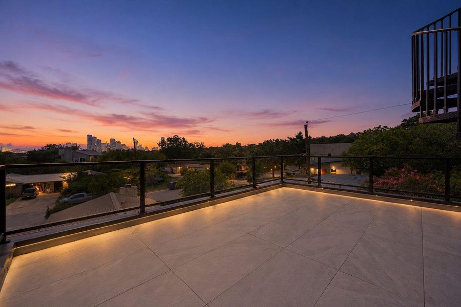 Watch the city skyline glow from this rooftop deck with glass railings and soft, integrated lighting. Watch the city skyline glow from this rooftop deck with glass railings and soft, integrated lighting.