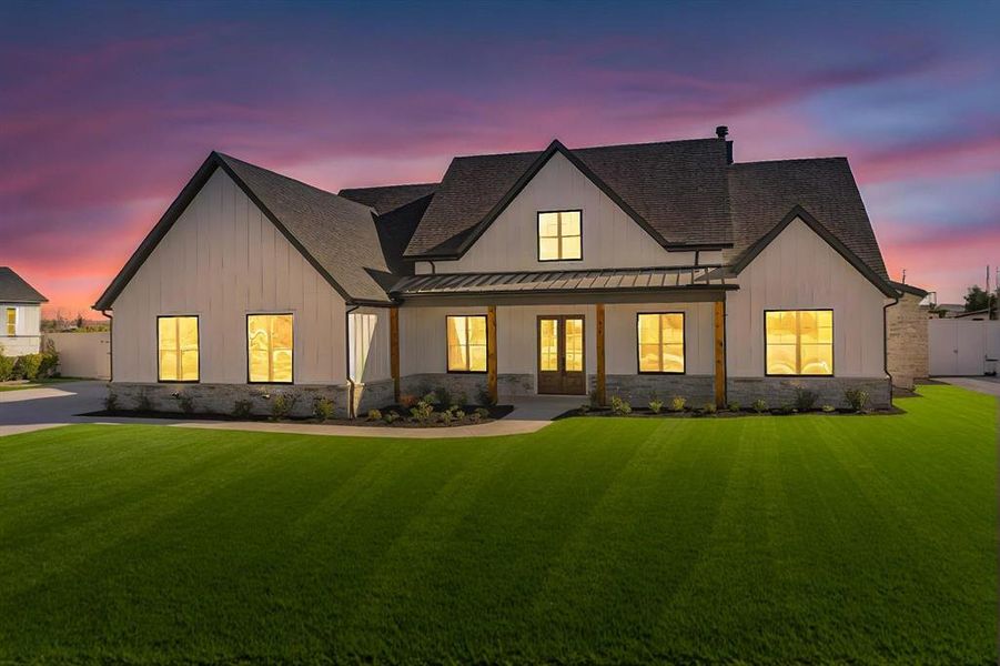 Back house at dusk featuring a yard