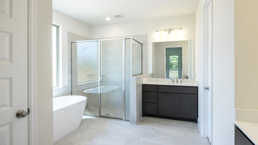 Full bath with vanity, a freestanding bath, a stall shower, and tile patterned flooring Full bath with vanity, a freestanding bath, a stall shower, and tile patterned flooring