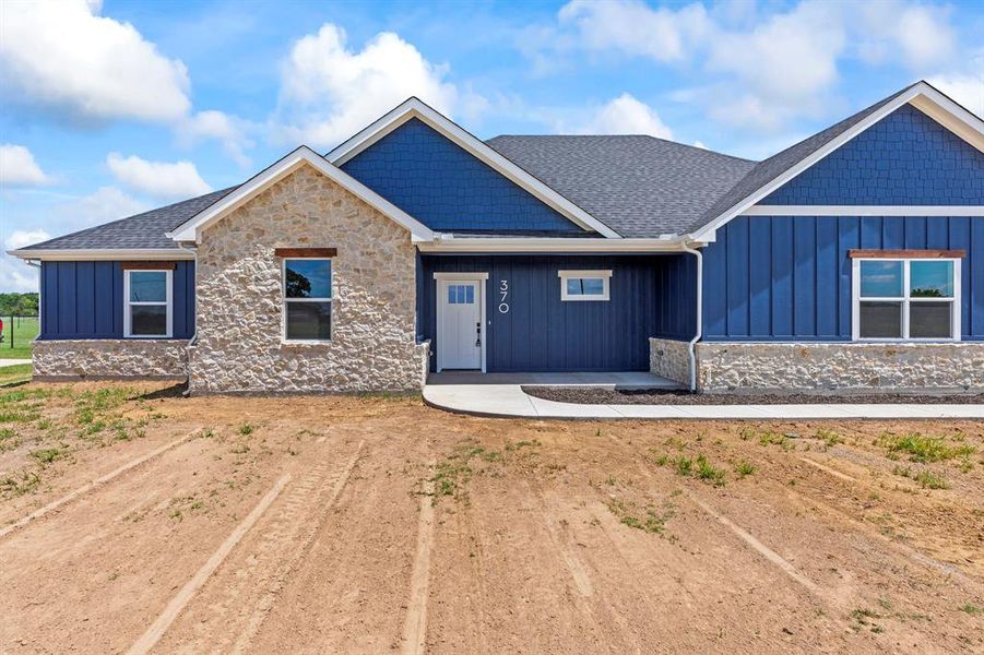 View of front facade with board and batten siding, stone siding, and roof with shingles