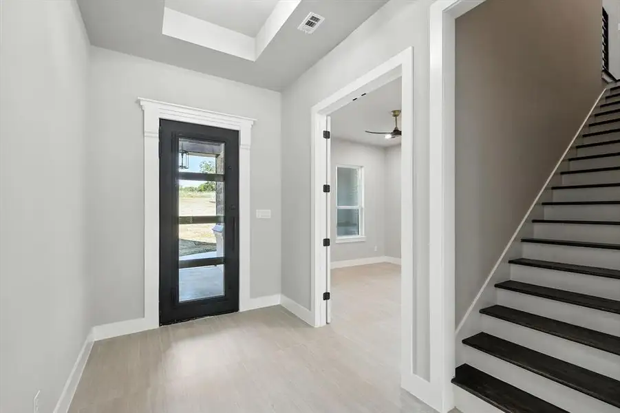 Entryway with stairs, a tray ceiling, and a ceiling fan Entryway with stairs, a tray ceiling, and a ceiling fan