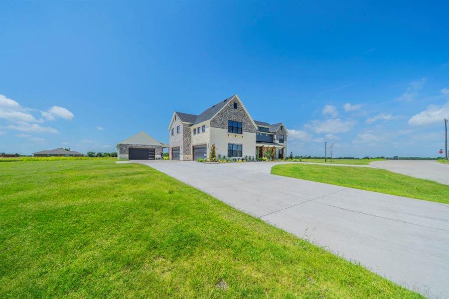View of front of home featuring stone siding, a front yard, and asphalt driveway View of front of home featuring stone siding, a front yard, and asphalt driveway