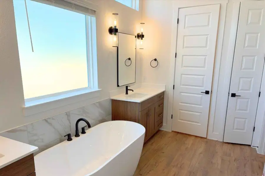 Bathroom featuring vanity, a freestanding tub, light wood-style flooring, and tile walls Bathroom featuring vanity, a freestanding tub, light wood-style flooring, and tile walls