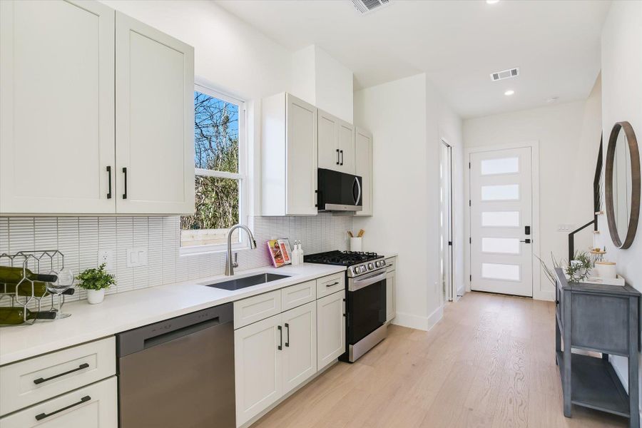 This bright kitchen features crisp shaker cabinetry, matte black hardware, and a classic tile backsplash.