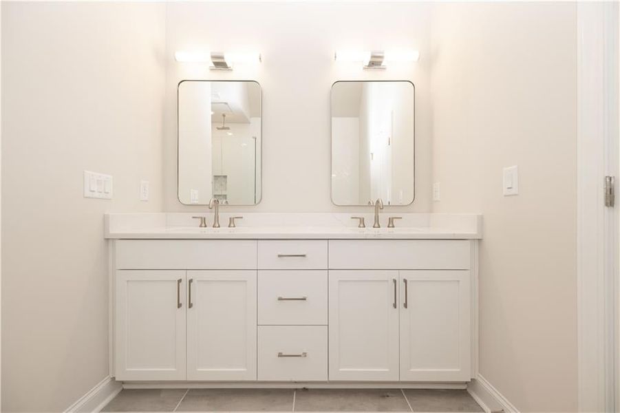 Full bath with double vanity and light tile patterned flooring