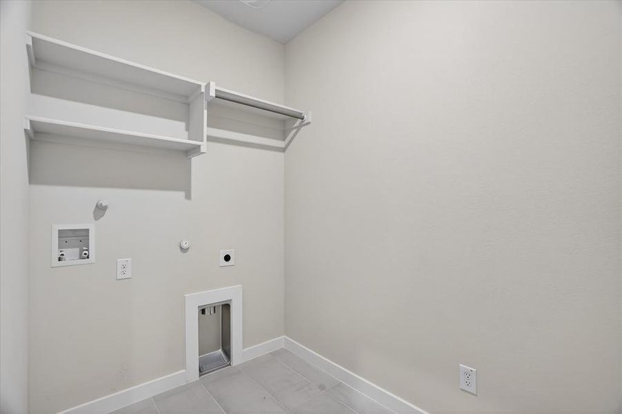 Dedicated laundry area featuring light-toned walls, white trim, and light grey tile flooring