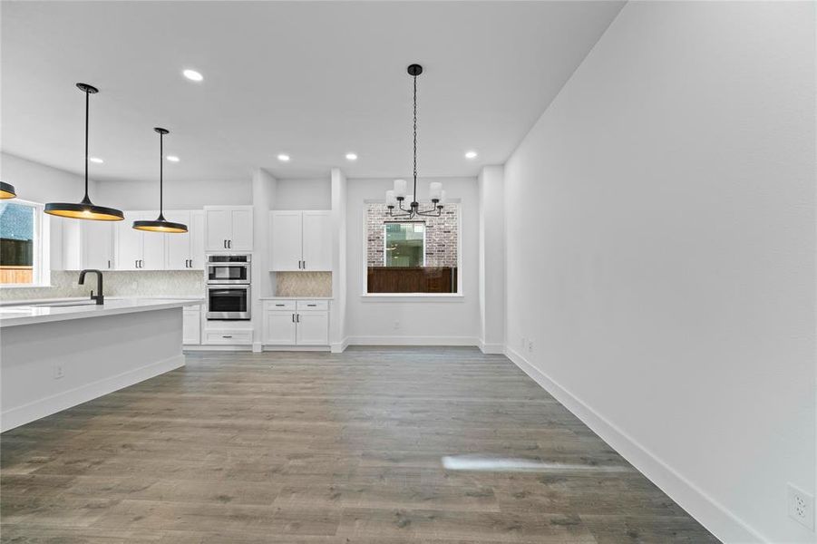 Kitchen featuring decorative backsplash, white cabinetry, a chandelier, light countertops, and recessed lighting Kitchen featuring decorative backsplash, white cabinetry, a chandelier, light countertops, and recessed lighting