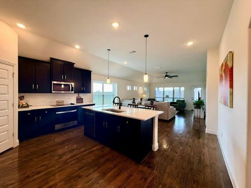 Open-concept kitchen featuring dark cabinetry, white countertops, subway tile backsplash, and stainless steel appliances Open-concept kitchen featuring dark cabinetry, white countertops, subway tile backsplash, and stainless steel appliances