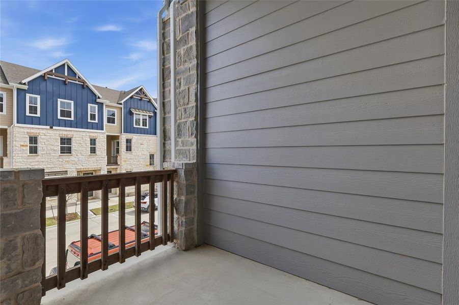 The property features a balcony with a concrete floor and a wooden railing, supported by stone pillars