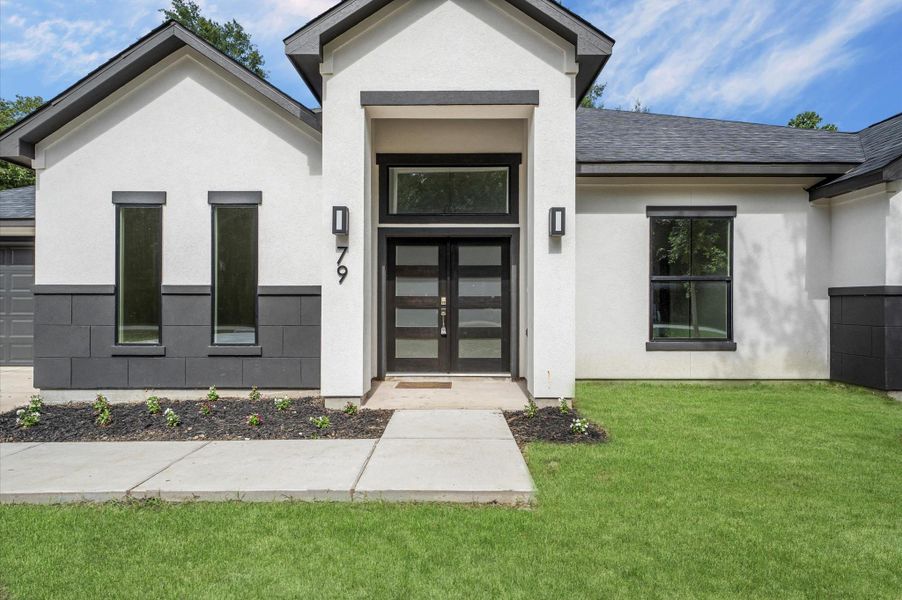 This modern home features a clean, contemporary facade with a combination of white and dark gray exteriors. The entrance is highlighted by a sleek glass door and symmetrical windows, complemented by well-maintained landscaping and a neat walkway. This modern home features a clean, contemporary facade with a combination of white and dark gray exteriors. The entrance is highlighted by a sleek glass door and symmetrical windows, complemented by well-maintained landscaping and a neat walkway.