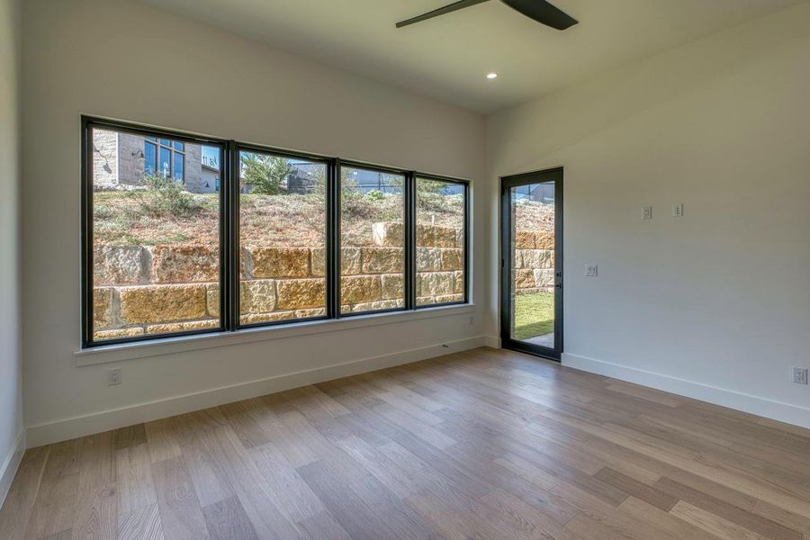 Large picture windows frame views of the stone retaining wall in this airy room. Large picture windows frame views of the stone retaining wall in this airy room.