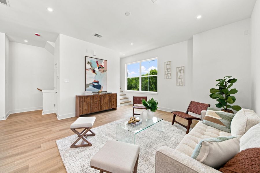 Natural light pours into thisinviting living room through anoversized window overlookingmature greenery. The open layout,warm wood-look flooring, neutralfinishes, and flexible furniturearrangement make the space idealfor conversation, movie nights,and effortless entertaining.