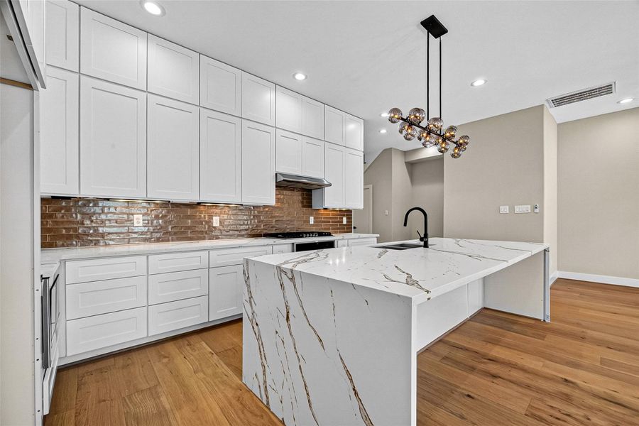 Modern kitchen featuring stainless steel appliances and a waterfall edge island with an integrated sink. Modern kitchen featuring stainless steel appliances and a waterfall edge island with an integrated sink.
