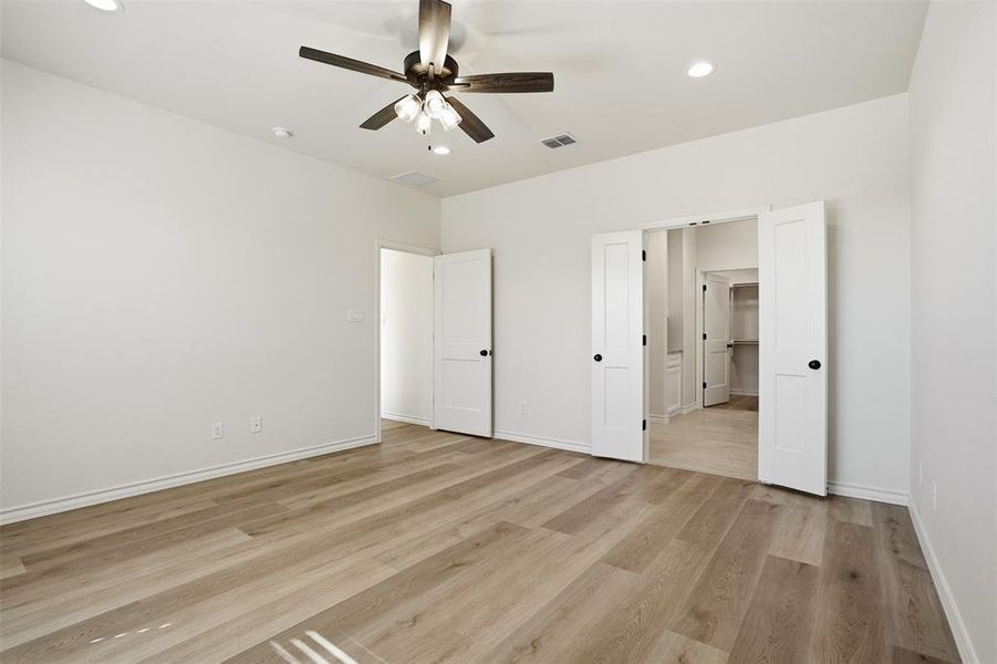 Unfurnished bedroom with ceiling fan, light wood-type flooring, and recessed lighting Unfurnished bedroom with ceiling fan, light wood-type flooring, and recessed lighting