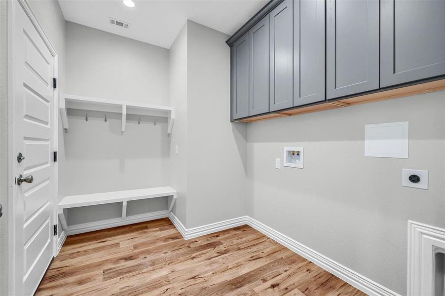 Washroom featuring electric dryer hookup, hookup for a washing machine, cabinets, and light wood-type flooring