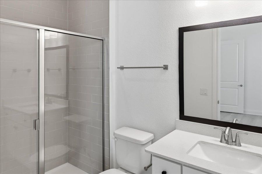 A well-appointed bath features a sleek glass-enclosed shower and modern vanity with ample counter space. A well-appointed bath features a sleek glass-enclosed shower and modern vanity with ample counter space.