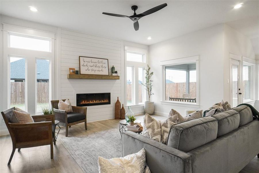 Living room with ceiling fan, a fireplace, and light hardwood / wood-style flooring