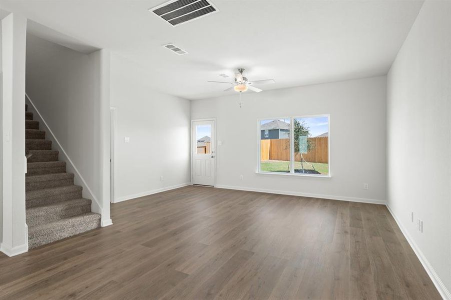 Unfurnished living room with a ceiling fan, dark wood-type flooring, and stairway