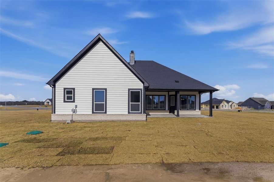 View of front of home with a front yard, a chimney, and a patio