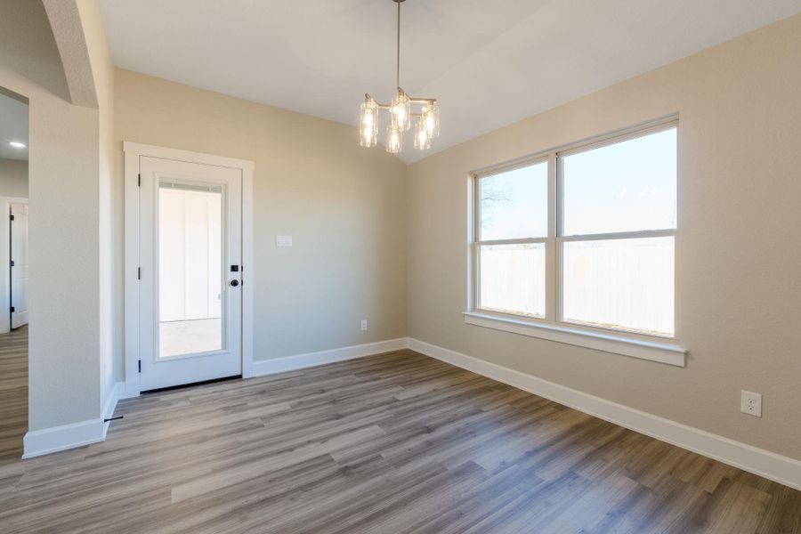 Unfurnished dining area with a chandelier, light wood finished floors, arched walkways, and vaulted ceiling