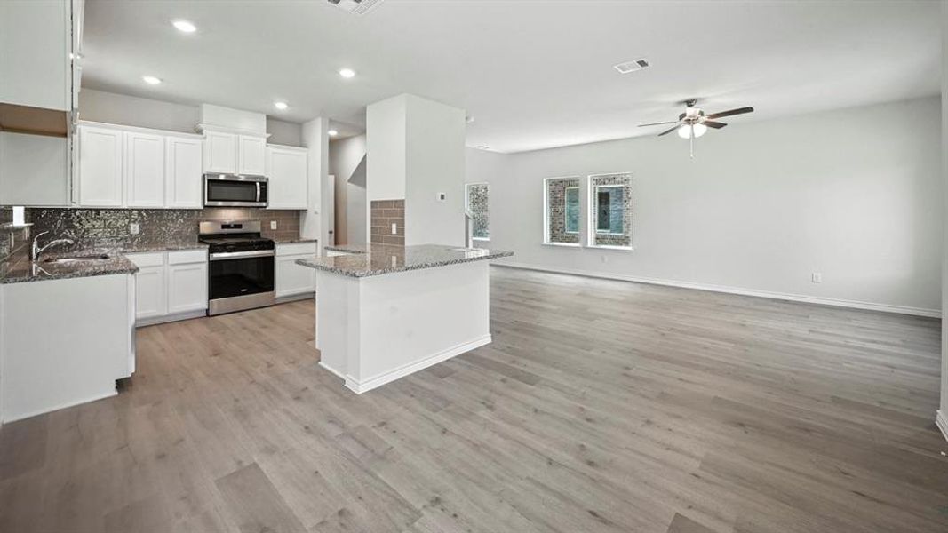 Kitchen featuring light stone counters, white cabinetry, appliances with stainless steel finishes, decorative backsplash, and recessed lighting