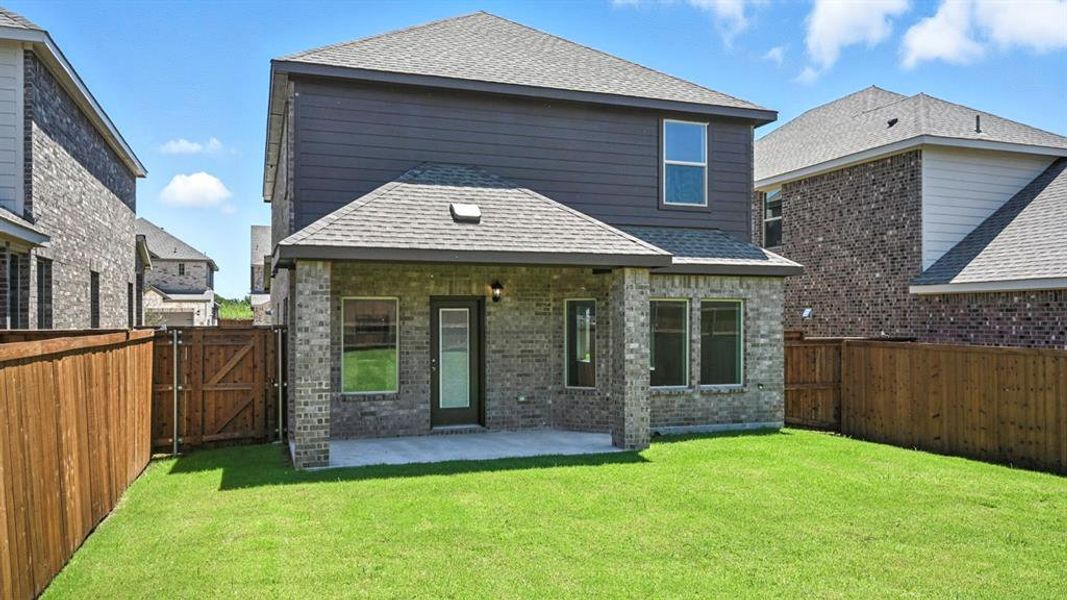 Back of property featuring roof with shingles, brick siding, a gate, and a fenced backyard