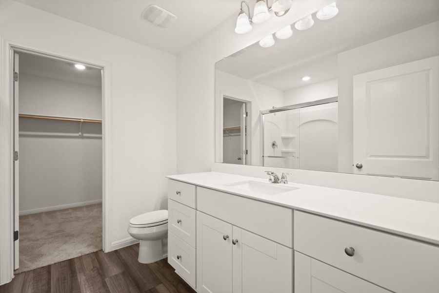 Bathroom featuring a spacious closet, a stall shower, vanity, dark wood finished floors, and recessed lighting