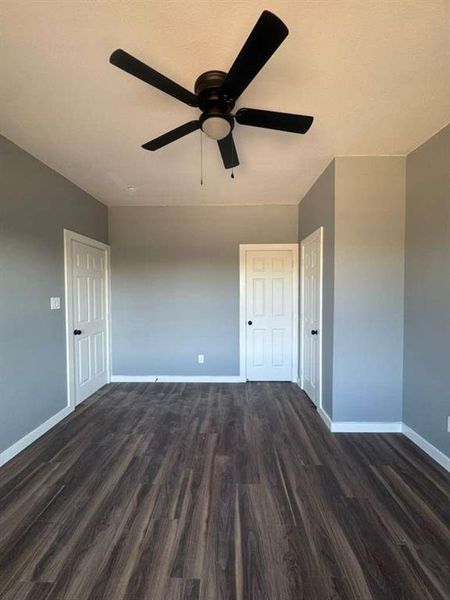 Unfurnished room featuring dark wood finished floors and ceiling fan