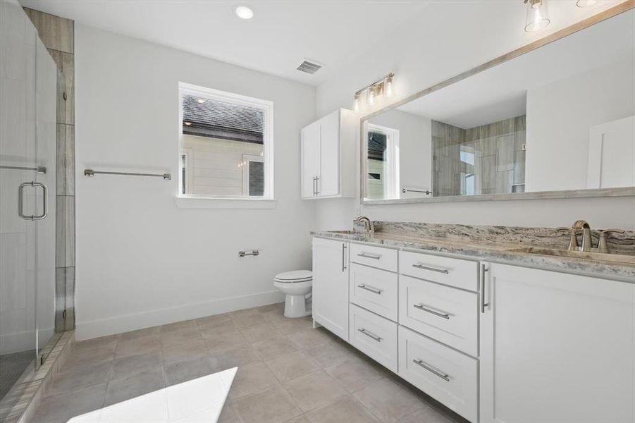 Bathroom with visible vents, a sink, a shower stall, and baseboards