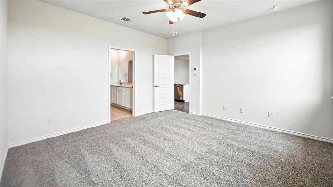 Spacious room featuring neutral carpeting, white walls, and a ceiling fan with integrated lighting