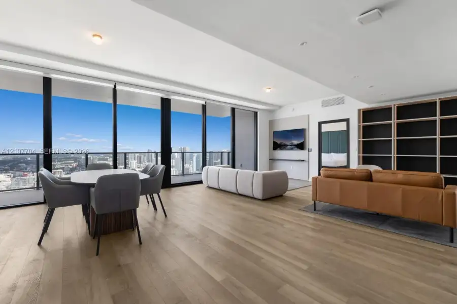 Floor-to-ceiling windows, wood-finish flooring, built-in shelving, recessed lighting, and a private balcony