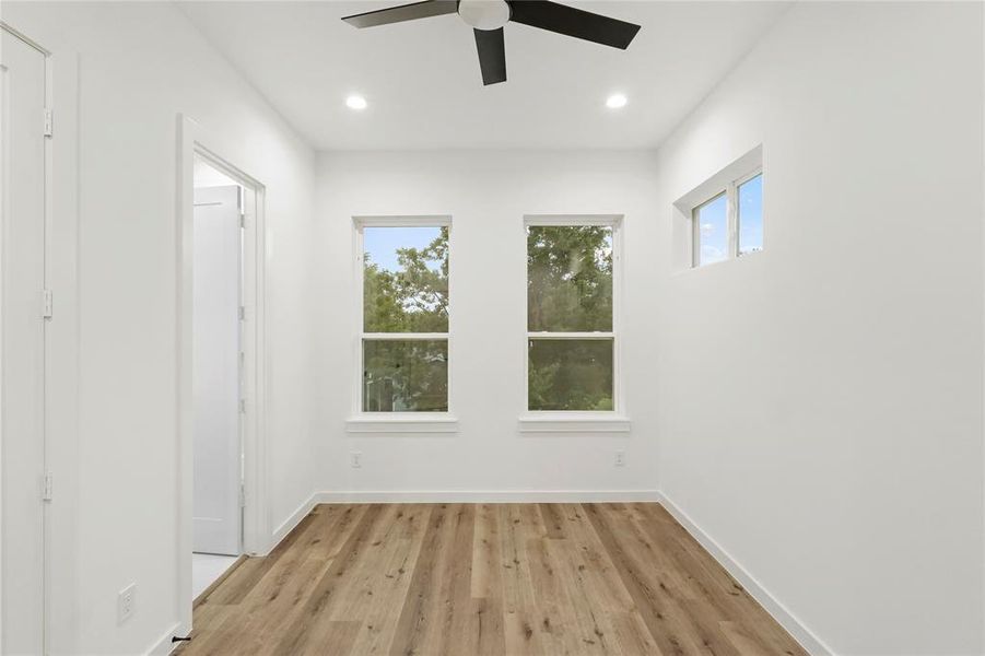 Spare room featuring a healthy amount of sunlight, light hardwood / wood-style floors, and ceiling fan