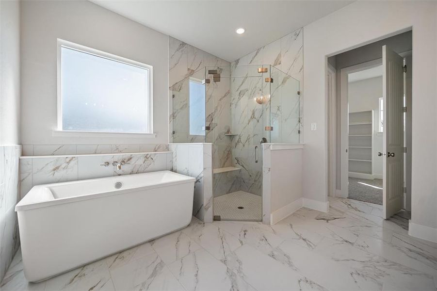 Bathroom featuring a marble finish shower, a freestanding bath, a spacious closet, light marble finish floors, and recessed lighting Bathroom featuring a marble finish shower, a freestanding bath, a spacious closet, light marble finish floors, and recessed lighting