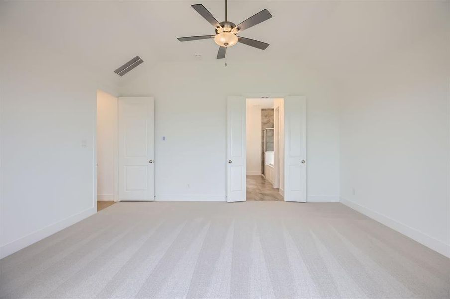 Unfurnished bedroom featuring lofted ceiling, light carpet, baseboards, and a ceiling fan