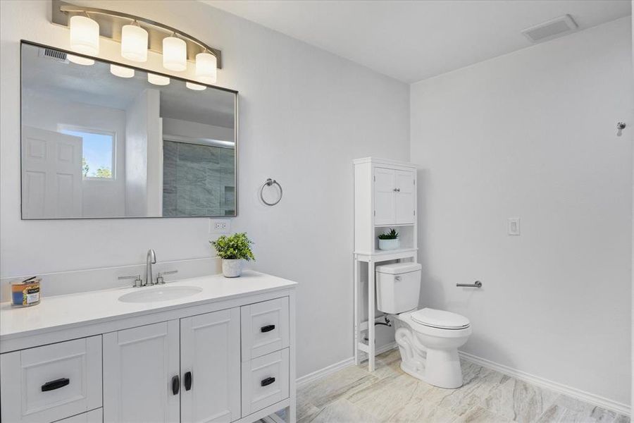 Bathroom featuring vanity, an enclosed shower, and toilet