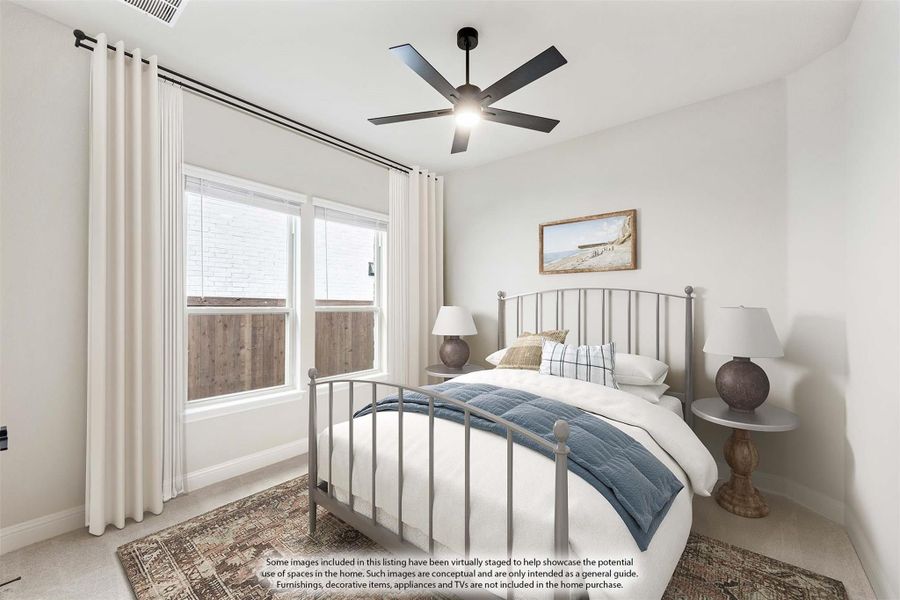 Bedroom with metal bed frame, ceiling fan, two windows with white curtains, and neutral carpet flooring