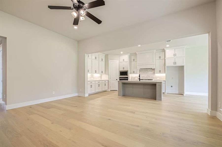 Kitchen with stainless steel microwave, backsplash, a ceiling fan, white cabinetry, and recessed lighting Kitchen with stainless steel microwave, backsplash, a ceiling fan, white cabinetry, and recessed lighting