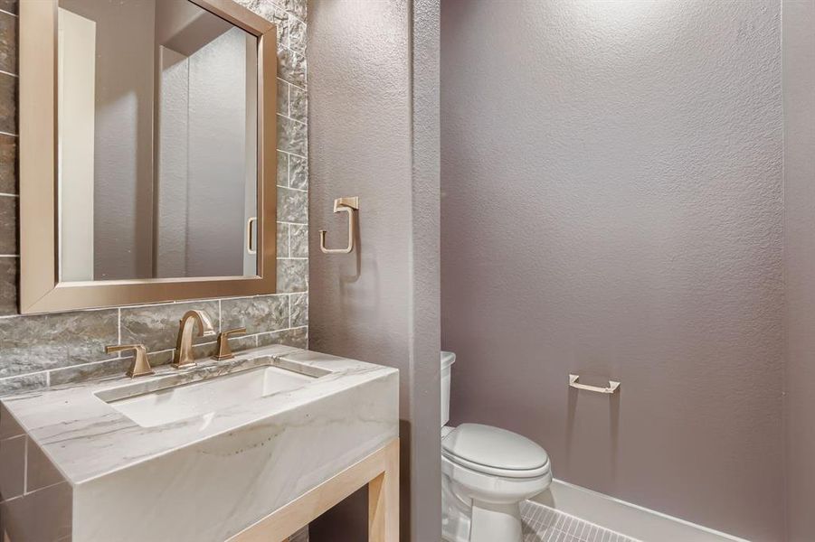 Half bath with backsplash, vanity, and a textured wall
