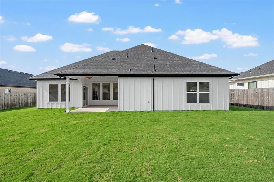 Rear view of house featuring a fenced backyard, a patio, roof with shingles, and board and batten siding Rear view of house featuring a fenced backyard, a patio, roof with shingles, and board and batten siding