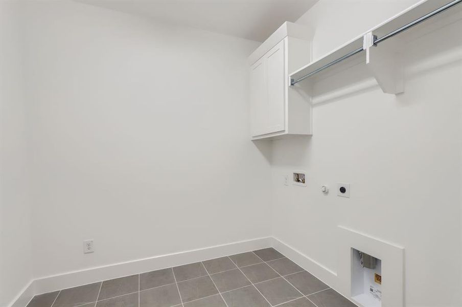 Laundry area with cabinets, hookup for an electric dryer, washer hookup, and dark tile patterned flooring