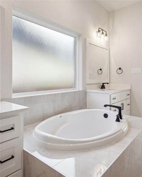 Bathroom with tiled bath and vanity