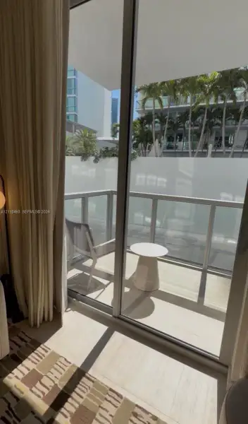 Floor-to-ceiling glass sliding doors opening to a private balcony with glass-panel railings and light-toned flooring