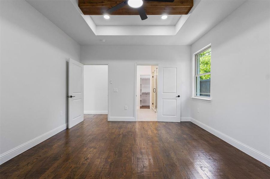 Unfurnished bedroom featuring a tray ceiling, wood finished floors, a walk in closet, ceiling fan, and recessed lighting Unfurnished bedroom featuring a tray ceiling, wood finished floors, a walk in closet, ceiling fan, and recessed lighting