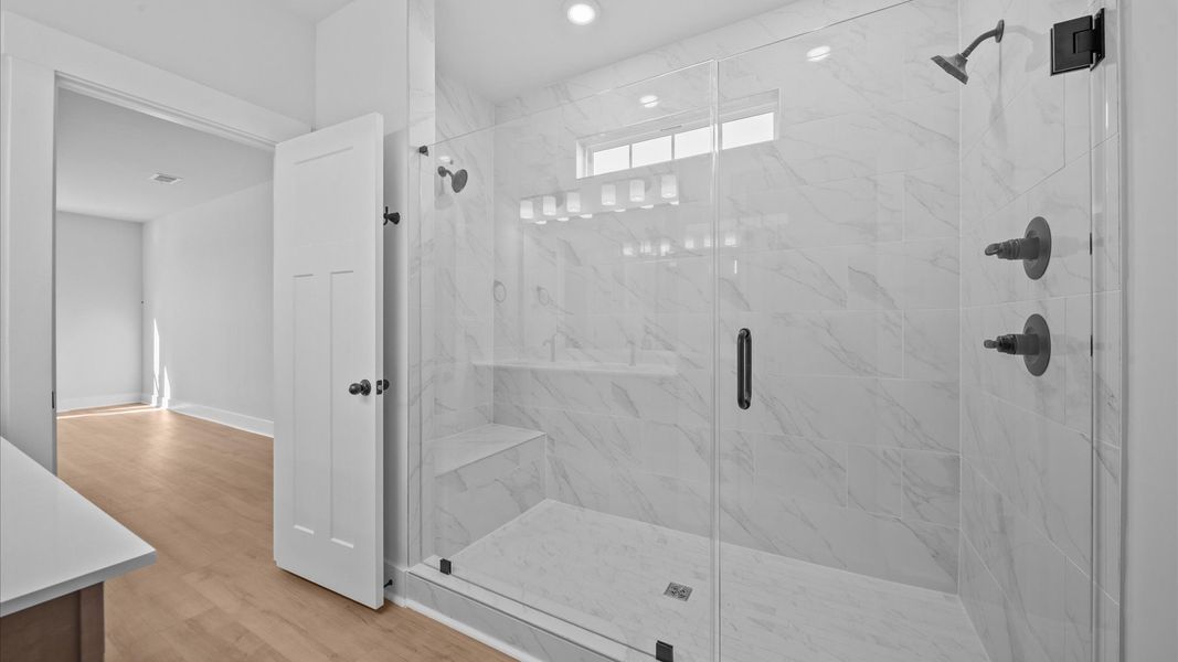 Spacious and modern primary bathroom with tiled walk-in shower and first-class double vanity setup