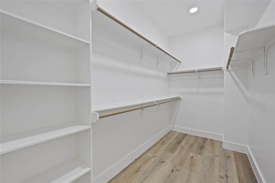 The oversized closet in the primary suite provides ample storage with built-in shelves and rods for hanging coats, dresses, and storing shoes and bags.