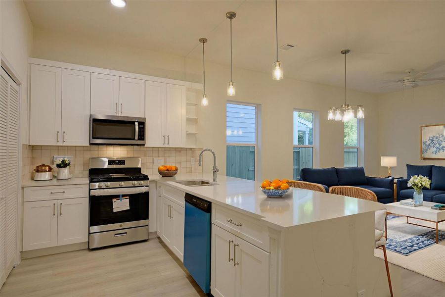 Bright, open kitchen with white Shaker cabinets,quartz counters, and a large island with sink andseating. Tile backsplash, pendant lighting, andstainless gas range/microwave plus dishwasher.Pantry closet nearby. Seamless flow to theliving/dining area with tall windows. Bright, open kitchen with white Shaker cabinets,quartz counters, and a large island with sink andseating. Tile backsplash, pendant lighting, andstainless gas range/microwave plus dishwasher.Pantry closet nearby. Seamless flow to theliving/dining area with tall windows.