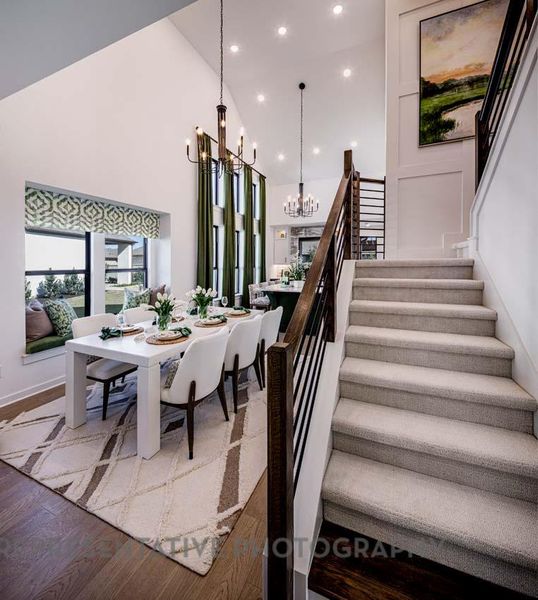 Dining area with a chandelier, stairs, wood finished floors, high vaulted ceiling, and recessed lighting
