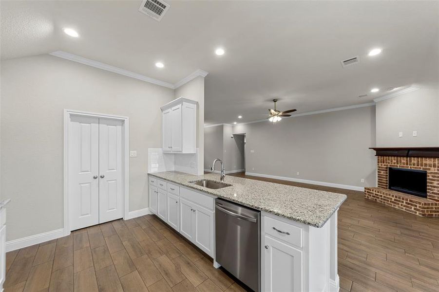 Kitchen island with a granite countertop, undermount sink, and stainless steel dishwasher